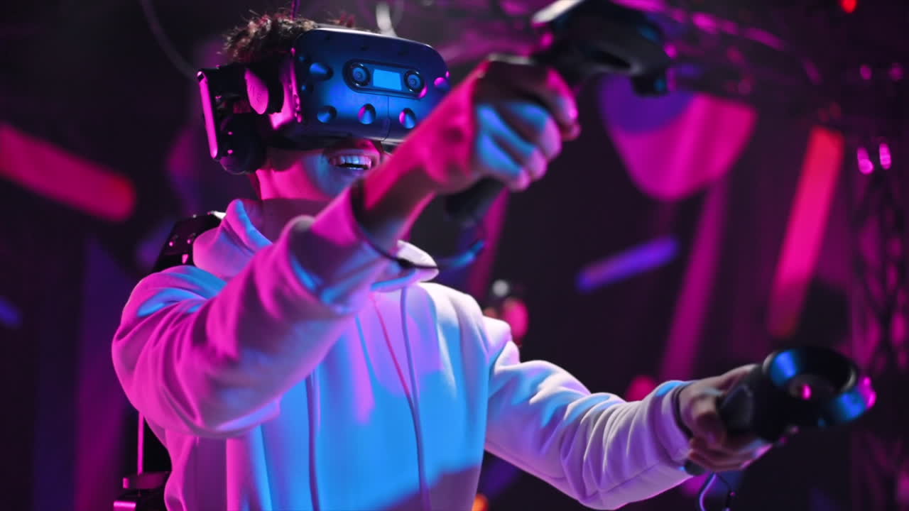 A joyful, interested boy is playing on VR treadmill with helmet, controllers and a backpack. Other people playing nearby. Slow motion