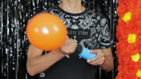 inflating orange balloon with hand pump for día de muertos party