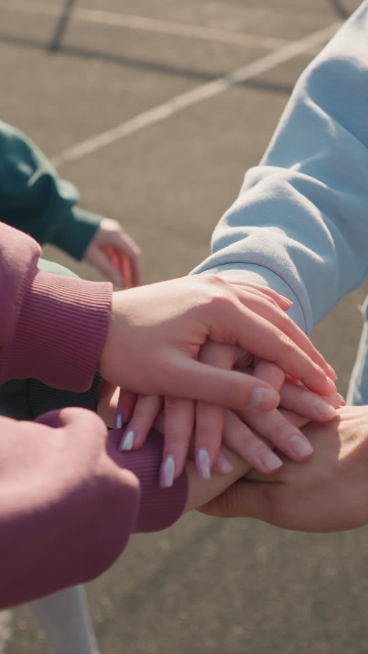 cerca de las manos de personas con capuchones que se unen como un equipo durante un juego de voleibol al aire libre, simbolizando la unidad, el trabajo en equipo y la colaboración bajo un cielo brillante en un entorno al aire libre