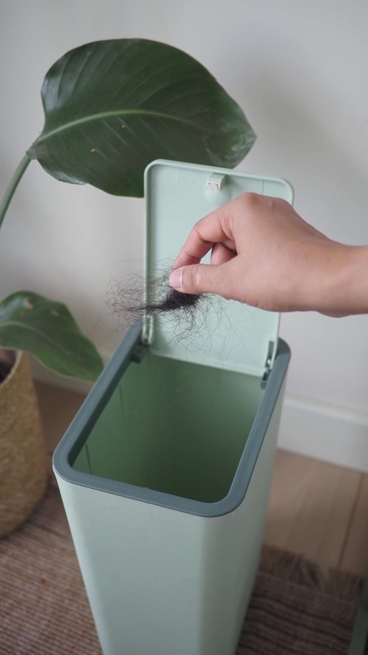 Persona che getta i capelli in un moderno cestino dei rifiuti