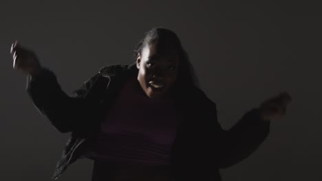 studio portrait shot of young woman dancing with low key lighting against grey background 6