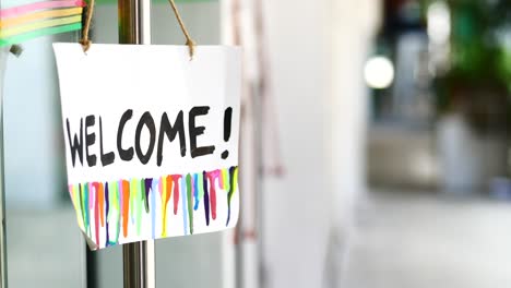 welcome hand written text on paper hanging on cafe door