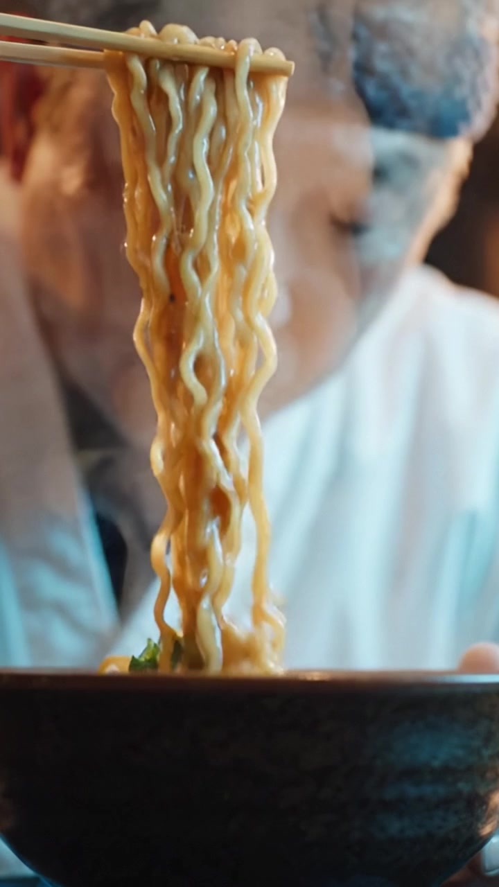 Un artigiano culinario concentrato prepara e gusta con cura noodles tradizionali, enfatizzando precisione, sapore e l'arte della cucina asiatica in ogni delizioso boccone.
