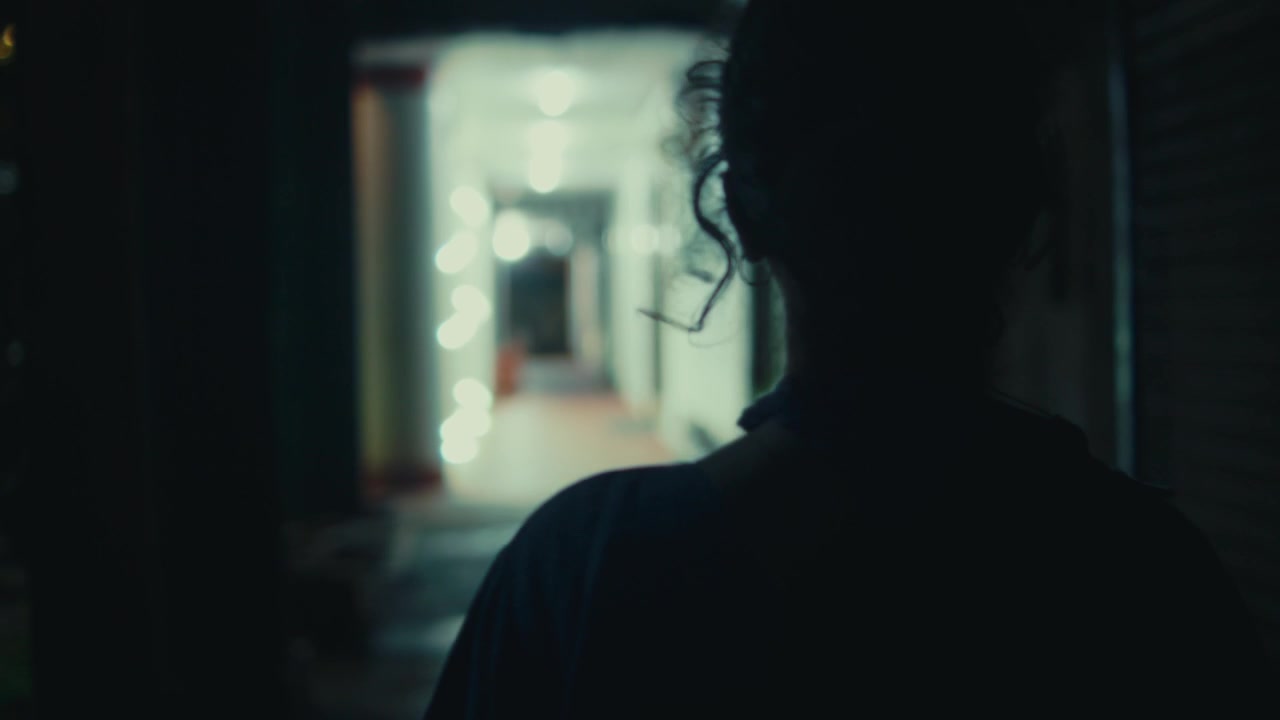 Silhouette di una persona che cammina attraverso un vicolo urbano poco illuminato di notte