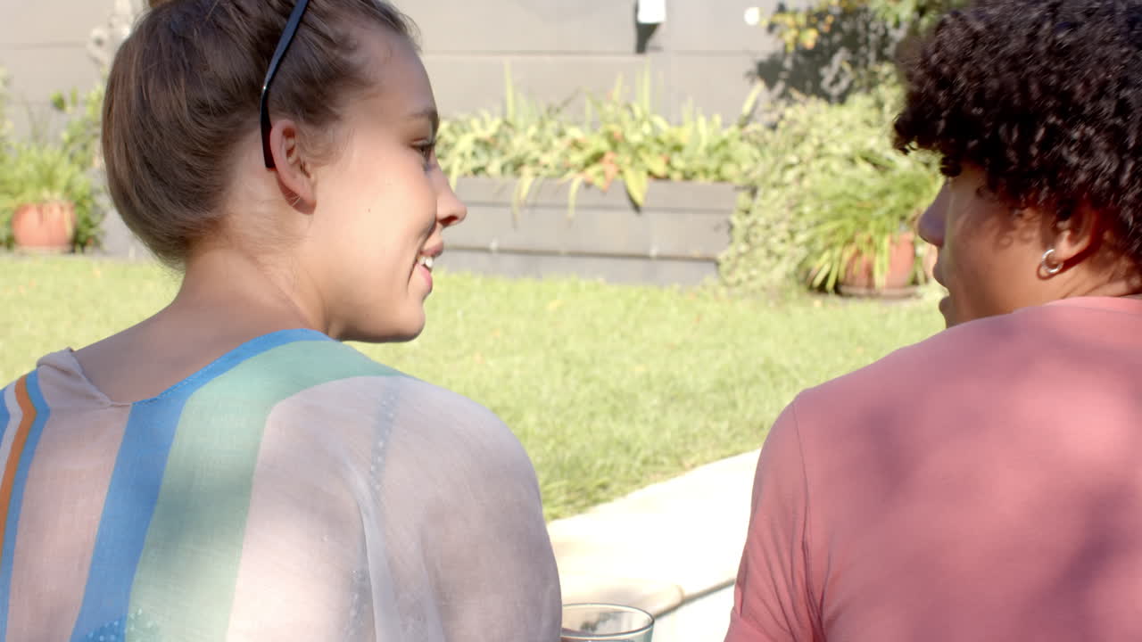Diverse couple relaxing by pool, enjoying conversation and sunshine on summer day, copy space