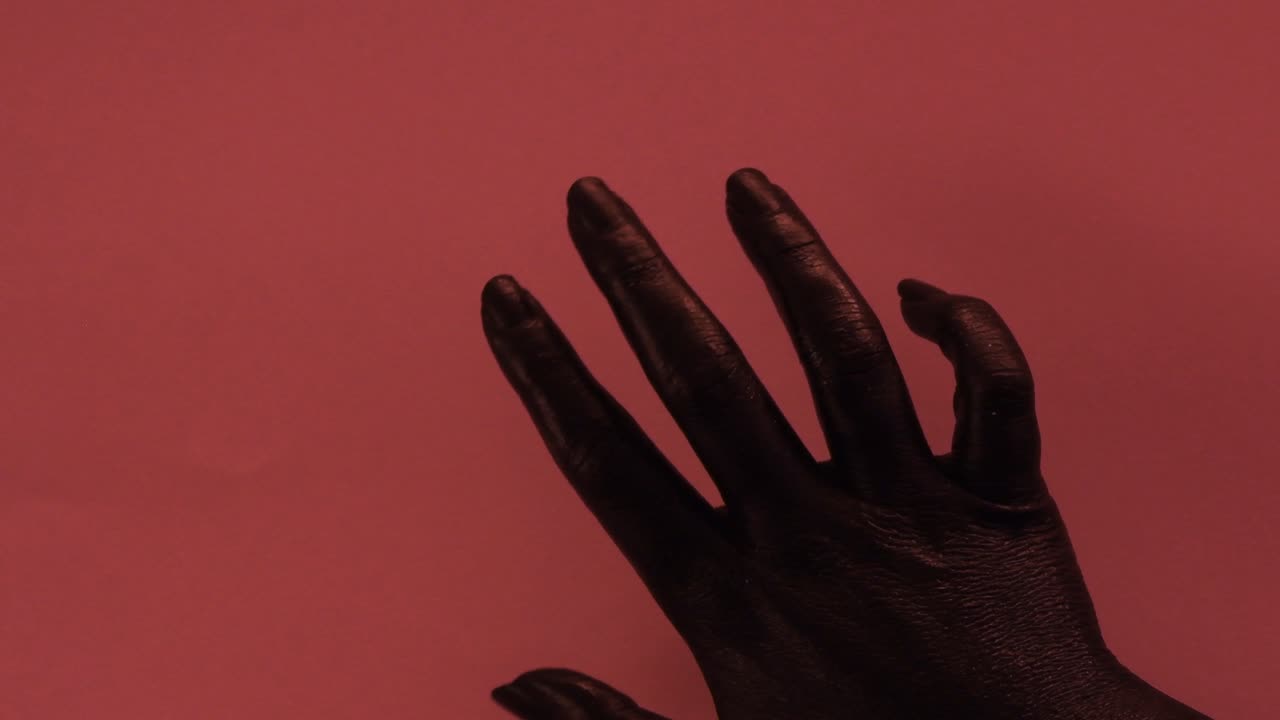 mujer joven pintada a mano con color negro moviéndose suavemente en un fondo rosa