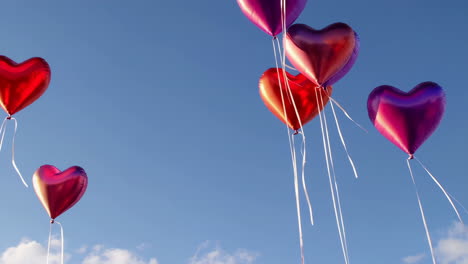 heart-shaped balloons floating in a clear blue sky