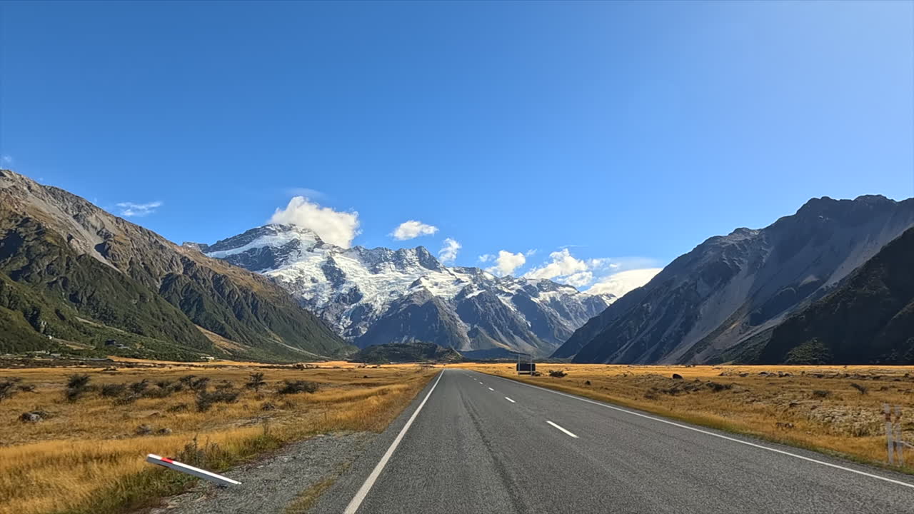 Scenic Road Leading Towards Majestic Snow-Capped Mountains
