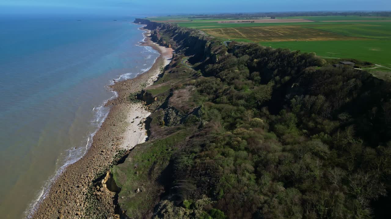 Coastal cliffs and sea at Longues-sur-Mer, Normandy, France. Aerial drone sideways