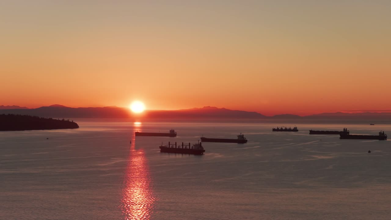 Telephoto wide panning aerial shot of ships in the Burrard Inlet during sunset in Vancouver, British Columbia, Canada. 4K