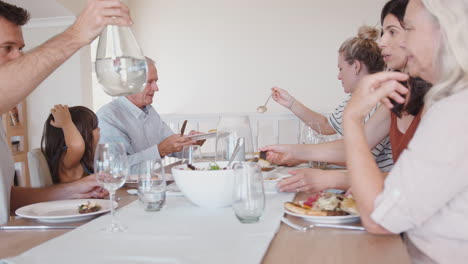 multi generation family sitting around table at home eating meal together