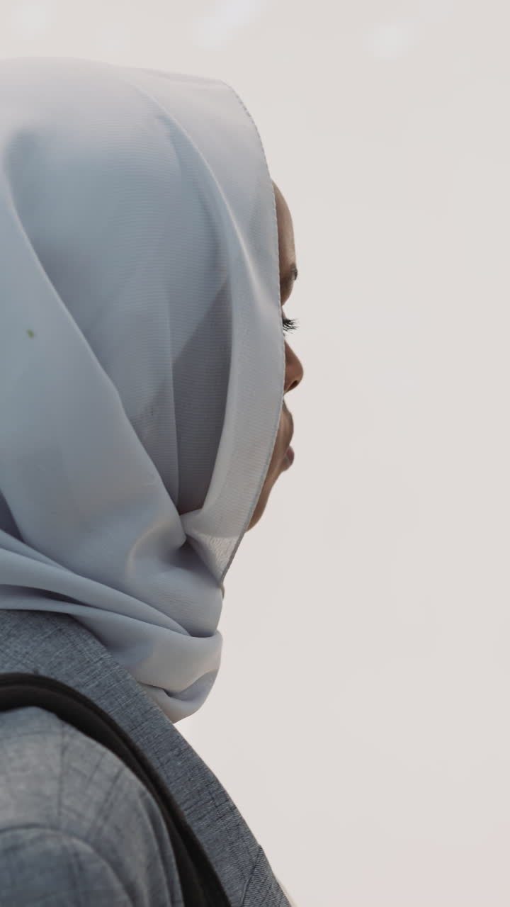 Black woman with hijab looks at bikini swimsuit in fashion store show window closeup slow motion. Muslim lady hesitates choosing new clothes and accessories