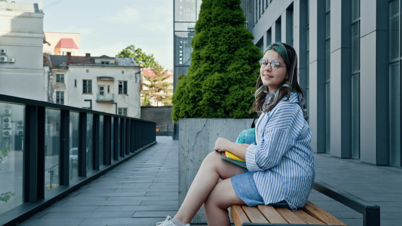 una adolescente sentada en un banco fuera de un edificio