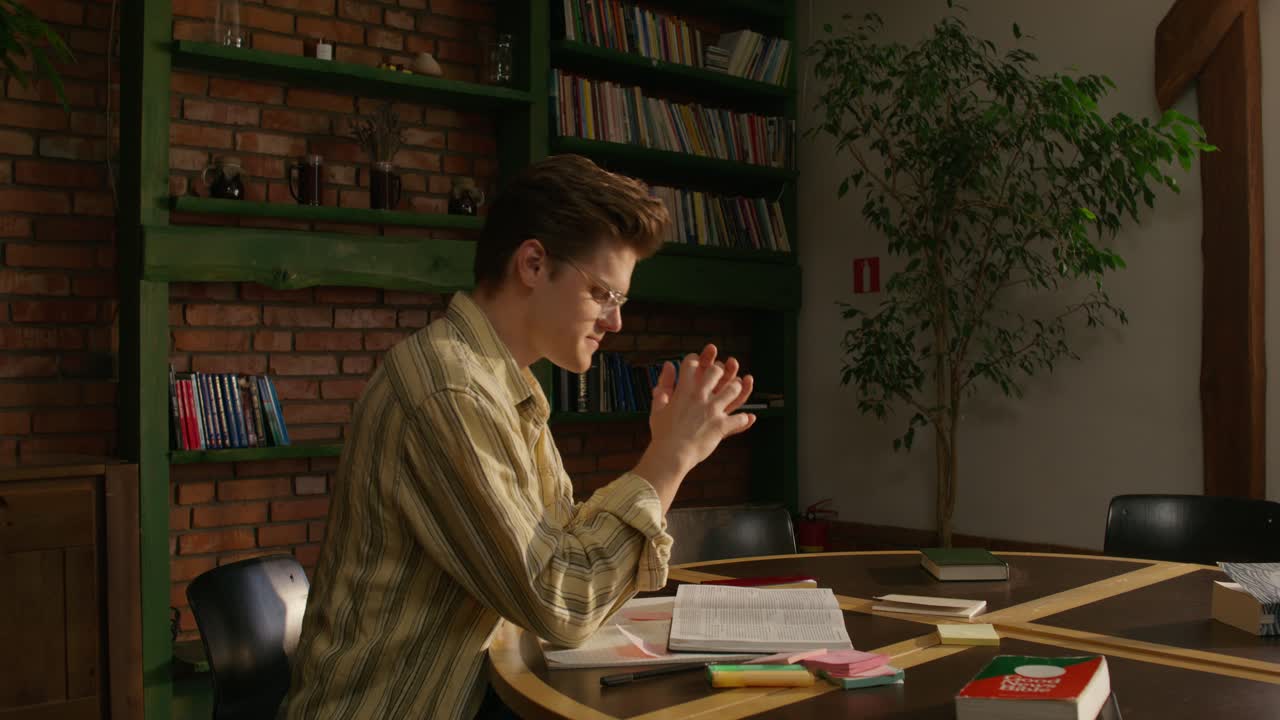 젊은이가 도서관 같은 환경에서 기도하고 공부하고 있습니다.