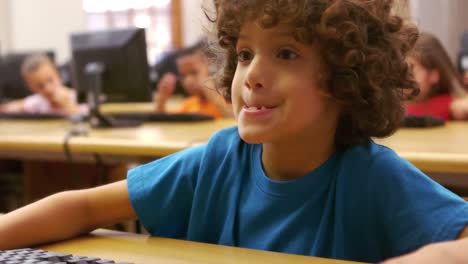 little boy using computer in classroom in school