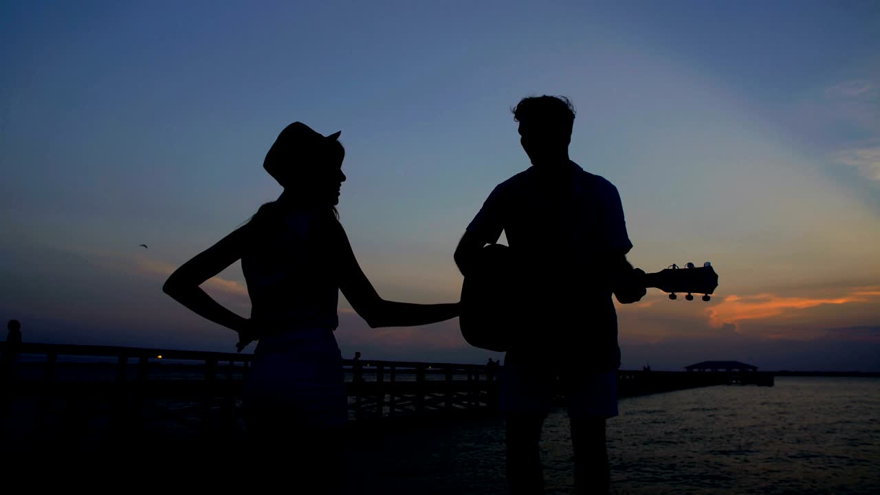 남자와 여자가 기타를 연주하면서 춤을 추는 실루