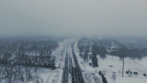 aerial view of a snow-covered country highway in south georgia. rare snowfall blankets the rural landscape. slow push-in drone movement captures serene winter scenery.