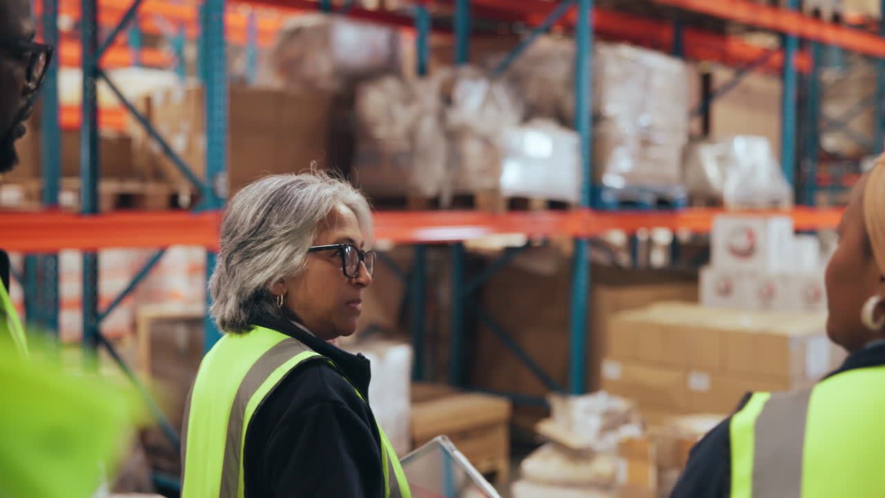 Warehouse Workers in Safety Vests Discussing Inventory with a Tablet