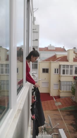 woman hanging clothes from window