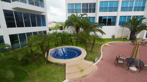 Vista-Aérea-De-La-Piscina-Redonda-Con-Jacuzzi-Y-Palmeras-En-Un-Apartamento-En-Punta-Centinela,-Ecuador.