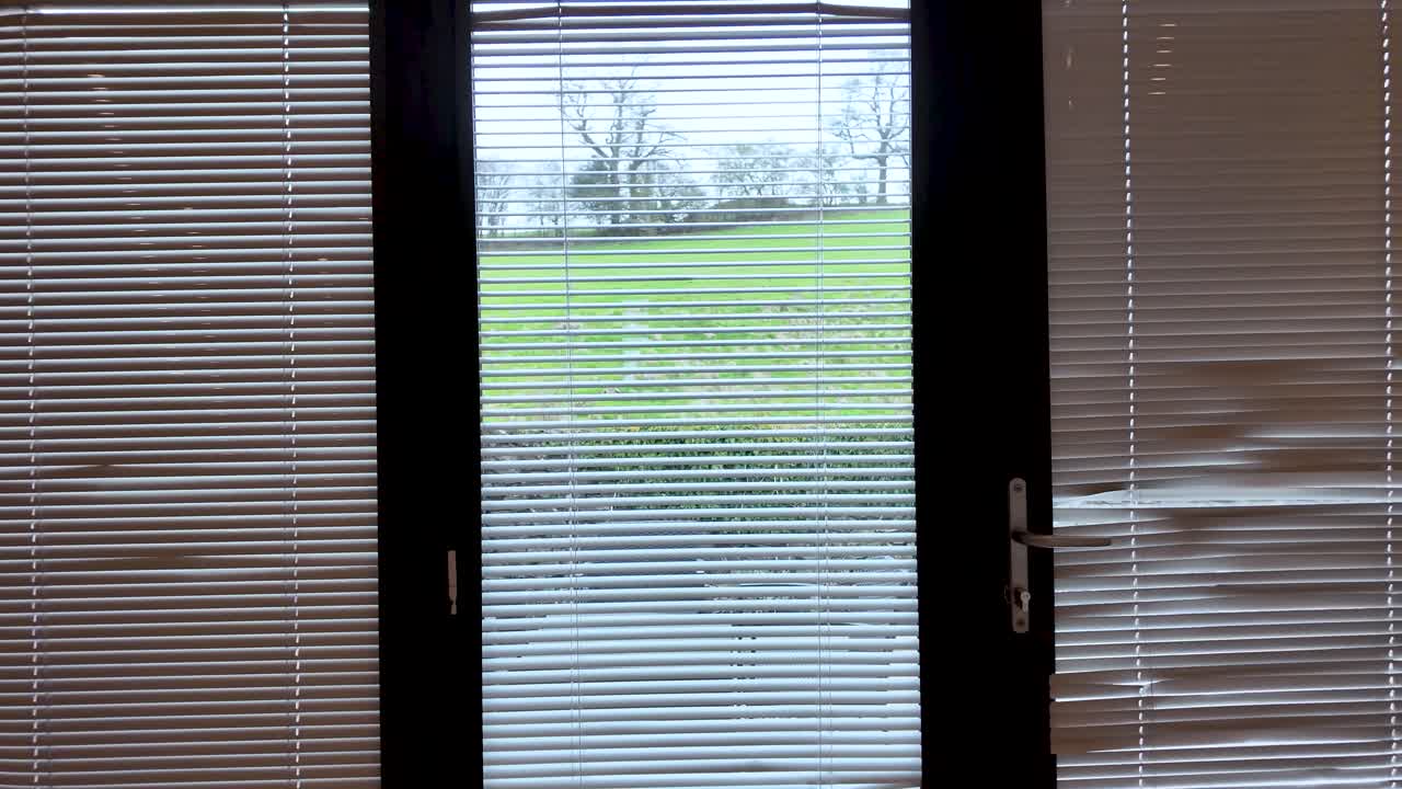 Blinds on bi fold glass doors controlling light and privacy with countryside view. push forward