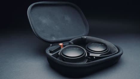 a product shot of black headphones on a black background, in a box. camera movement  from right to left.