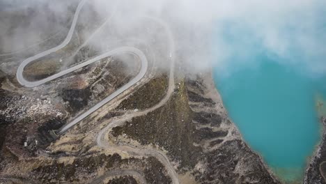 Drone-shot-of-a-road-in-the-mountains-of-Huaraz-Peru-next-to-a-blue-lagoon