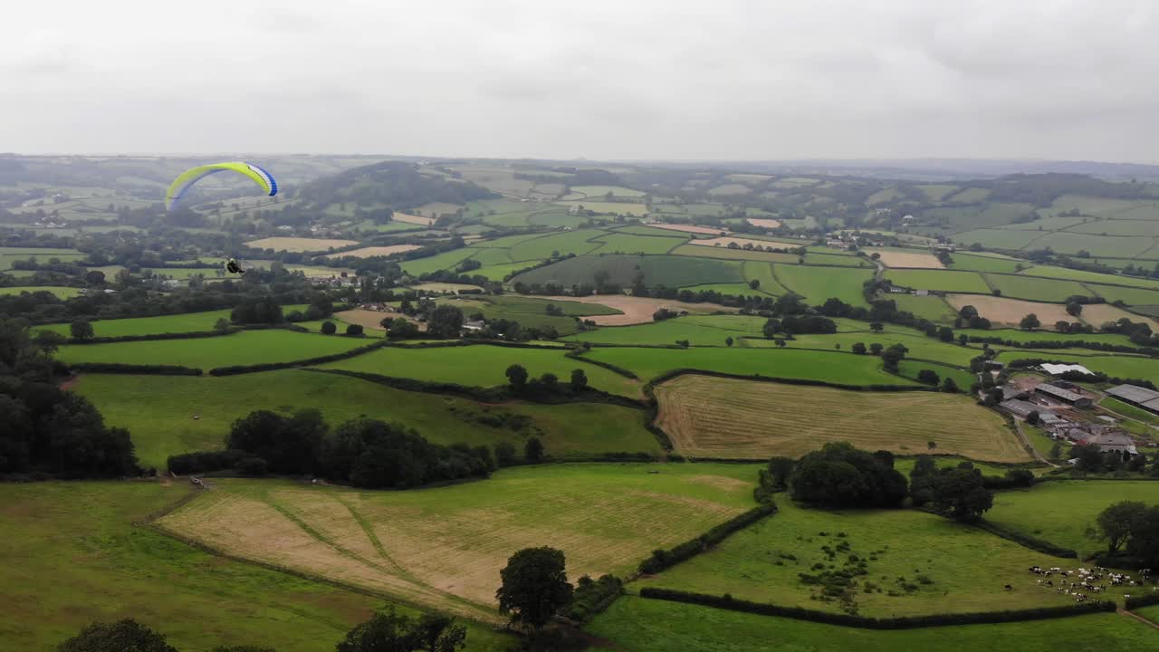 toma aérea de un parapente sobrevolando la campiña de devon en inglaterra