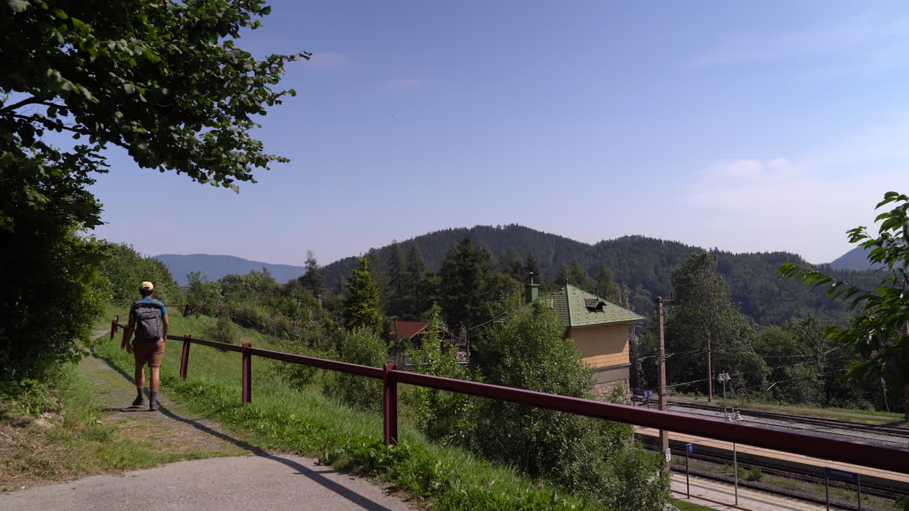 excursionista masculino caminando por el paisaje junto a las vías del tren