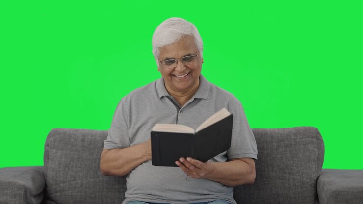 viejo indio feliz leyendo un libro en la pantalla verde de la mañana
