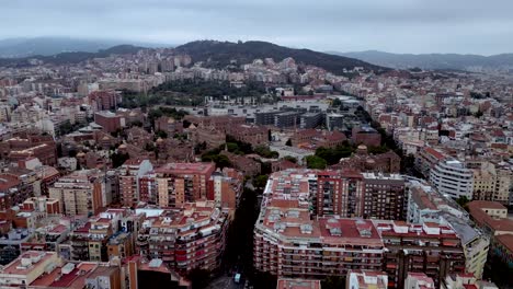 a cinematic aerial drone shots of barcelona city featuring high rise building both commercial and residential estate and the pyrenees mountain view in the background