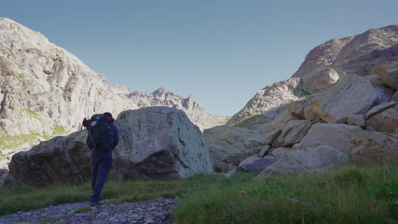 카메라에서 멀어져 바위 사이를 혼자 트레킹하는 남자