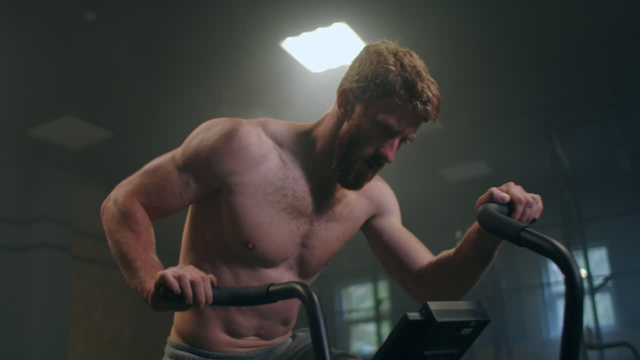 피트니스  ⁇  에서 정지 된 자전거 를 타고 피로 를 극복 하는 튼튼 한 사람