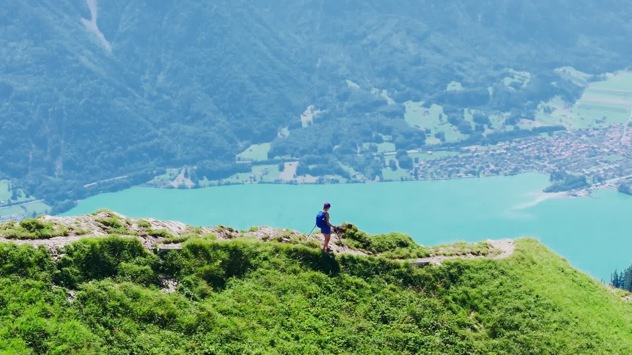 Hiker walks along the narrow Hardergrat ridge with Lake Brienz shimmering below