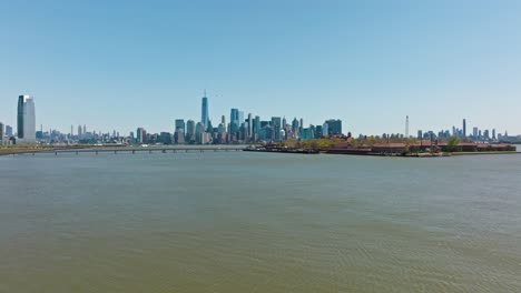 aerial approaching shot of ellis island with bridge and new york skyline in background