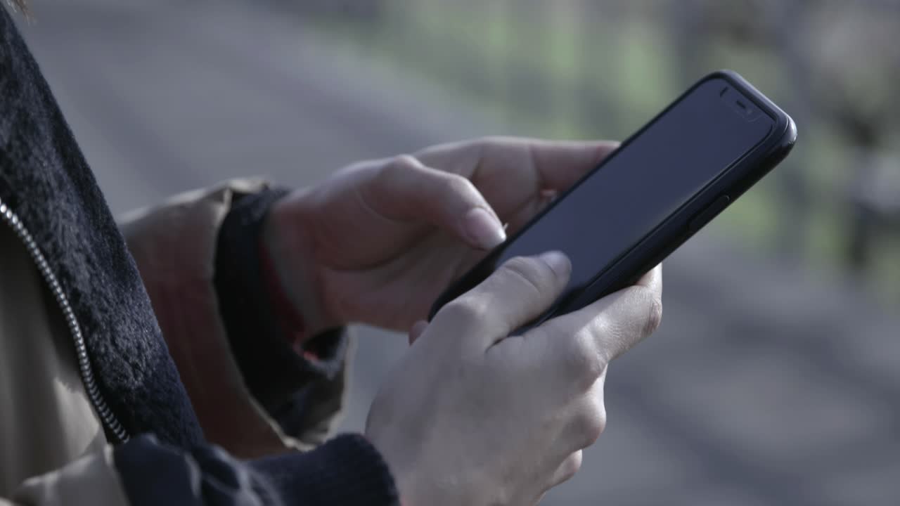Primo piano di mani che digitano e scorrono sullo schermo di uno smartphone
