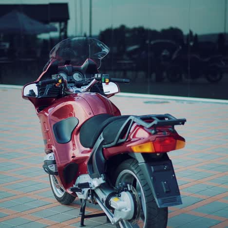 beautiful woman in a helmet is sitting behind a red motorbike in a black bodysuit against the background of a urban view