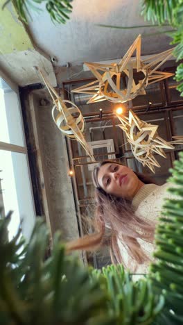 woman looking up at unique wooden decorations in a plant-filled cafe