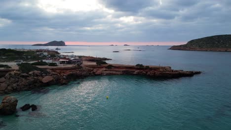 smooth aerial top view flight yoga girl position tree sunset cliff beach island ibiza spain descending drone