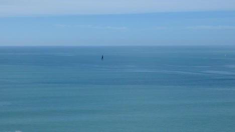 Yacht-moves-slowly-in-light-wind-on-calm-ocean-in-summertime---South-Pacific-Ocean,-New-Zealand