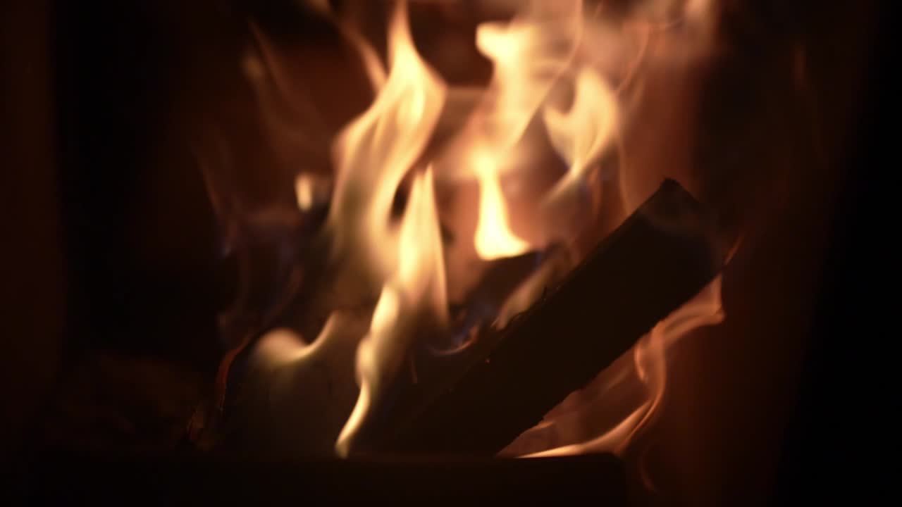 Closeup of burning wood inside in stunning slow motion with flickering flames.