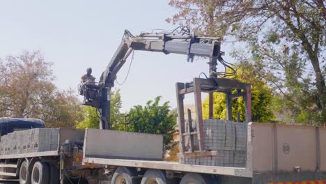 a person operating a truck-mounted crane to lift paving stones