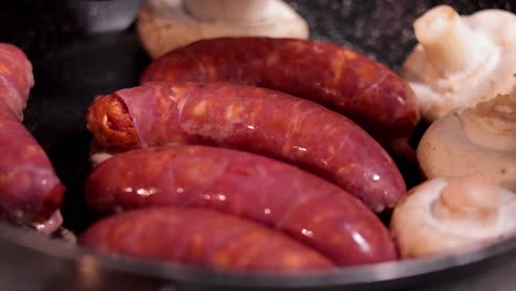 sausages and mushrooms being cooked in a pan