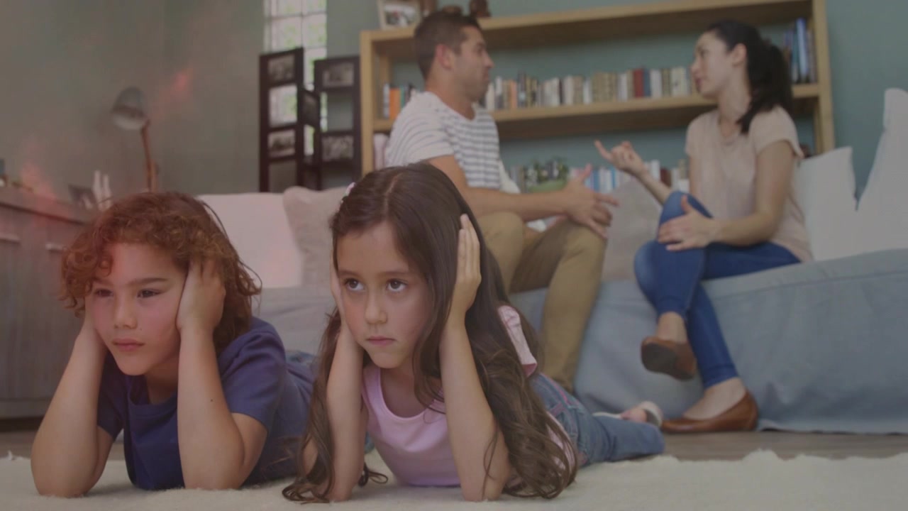 Parents commençant une dispute, enfants se couvrant les oreilles sur un tapis, portant un casque, bloquant le bruit pour leur santé