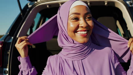 happy muslim woman in purple hijab posing in car trunk