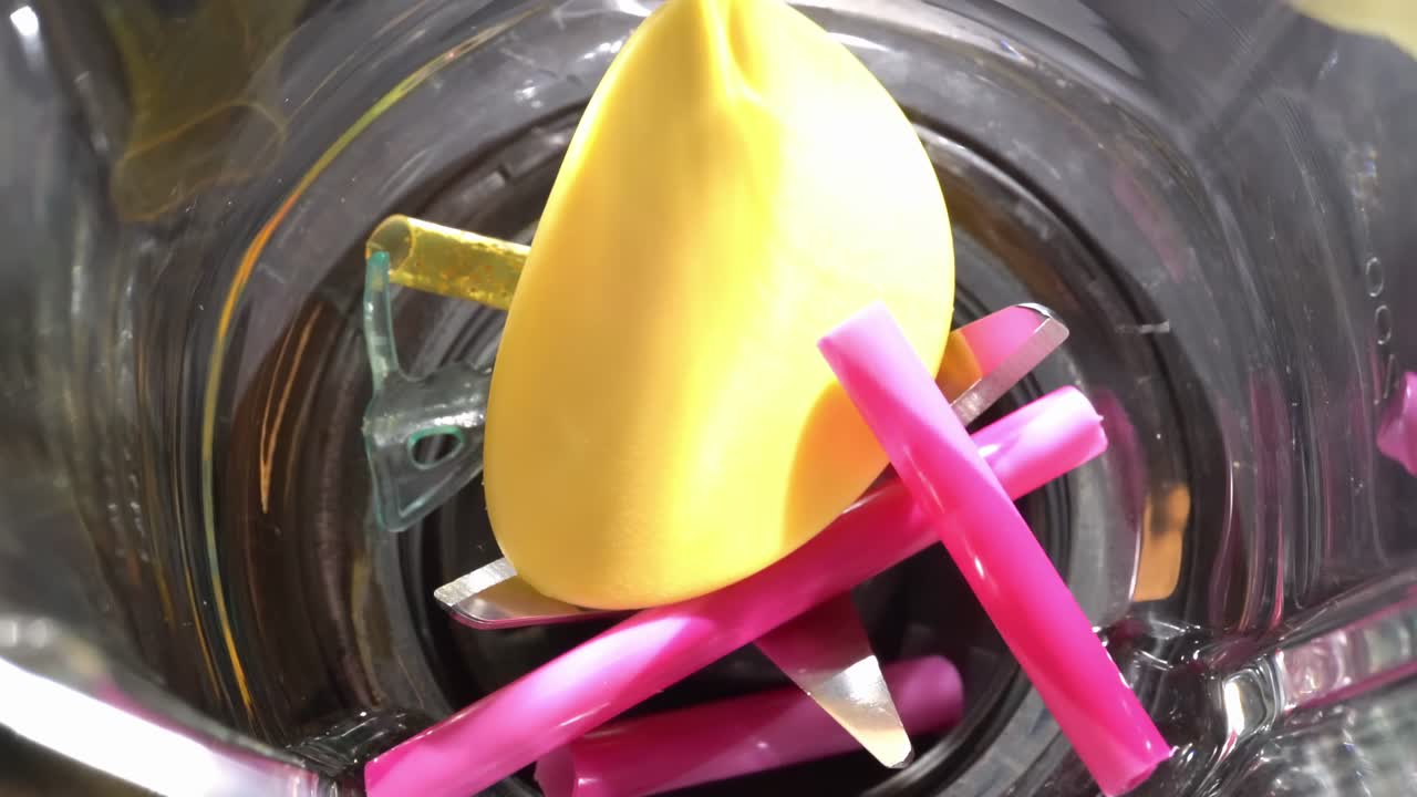 vista de arriba hacia abajo de objetos de plástico que caen en la licuadora en cámara lenta