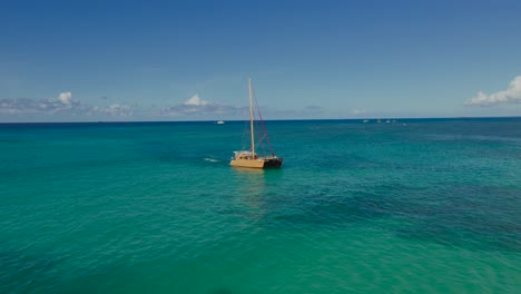 drone video of a wooden sailboat gliding across open turquoise sea near waikiki beach, oahu, hawaii. a tranquil aerial scene capturing island adventure, ocean clarity, and timeless maritime charm