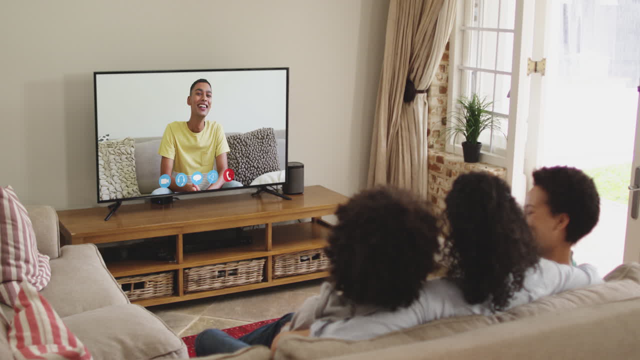 Famiglia afroamericana che fa una videochiamata in TV mentre è seduta sul divano a casa