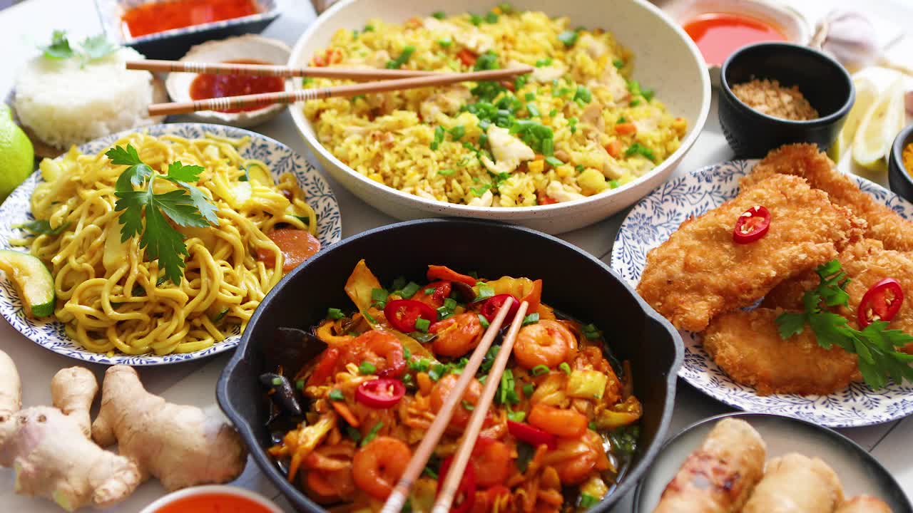 comida asiática servida platos sartenes y tazones llenos de fideos pollo salteado y verduras