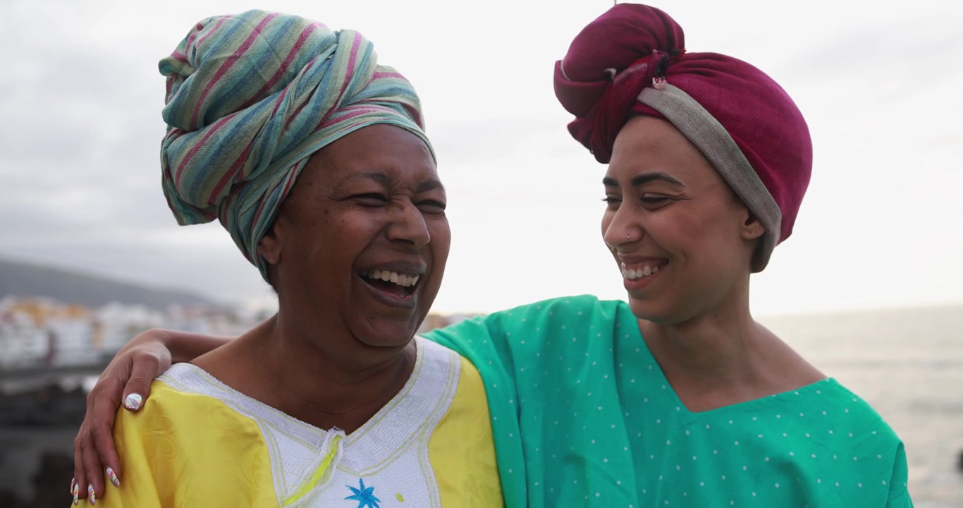 Mãe e filha africanas rindo juntas ao ar livre